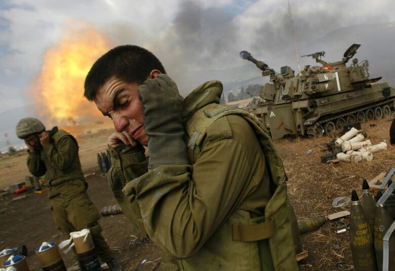 Israeli soldiers cover their ears as an artillery unit fires shells towards southern Lebanon from a position near Kiryat Shmona in northern Israel, near the border with Lebanon, on Friday, July 21, 2006. In the last 24 hours, at least six Israeli troops have been killed in pitched battles with Hezbollah militants and an Israeli helicopter pilot was killed when two Apache attack helicopters collided.