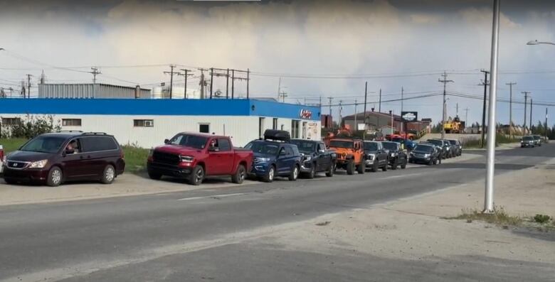 A long line of cars sit on the road.