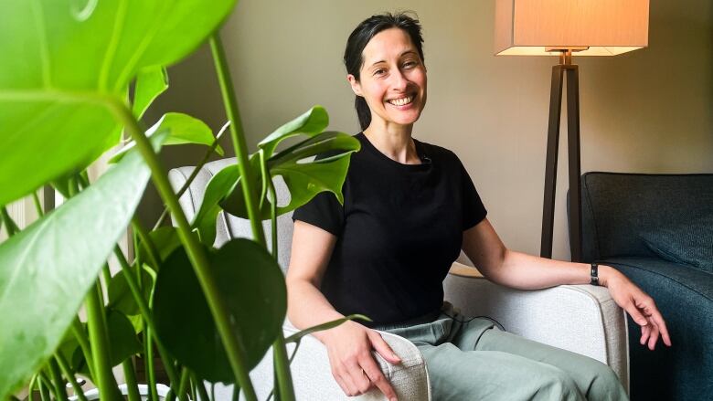 A woman is sitting in a chair and smiling at the camera.