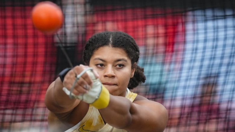 A female hammer thrower winds up to throw during an outdoor competition.