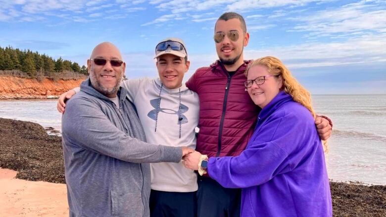 A family of four is shown on a beach.