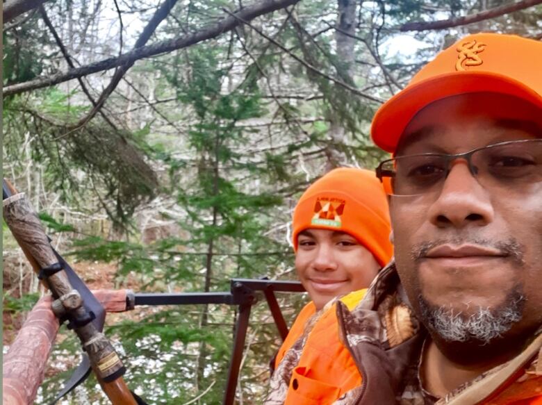 A man and his son are shown in orange hunting hats.