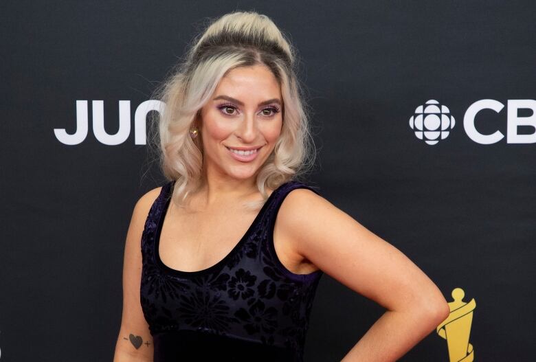 A woman in a black dress poses for cameras.