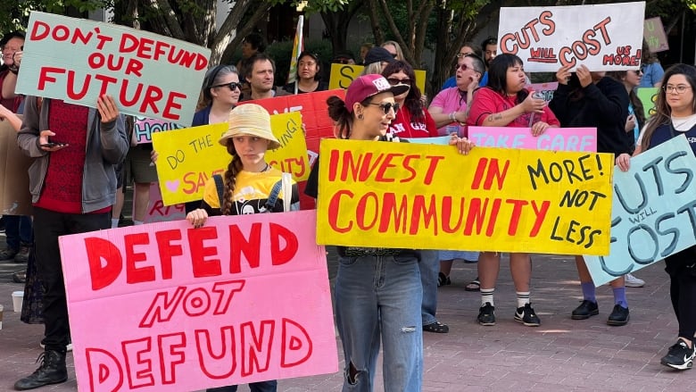 Several people gathered outside with colourful signs with messages like 