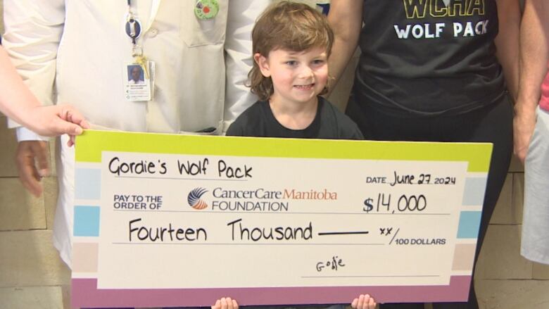 A little boy holds an oversized cheque