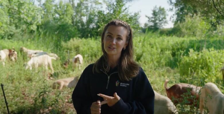 woman stands with goats in background