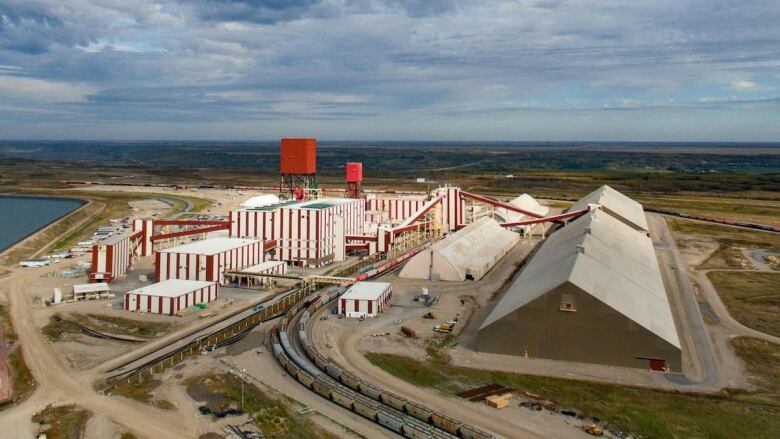 An aerial shot shows several red and white buildings in a large mining operation. 