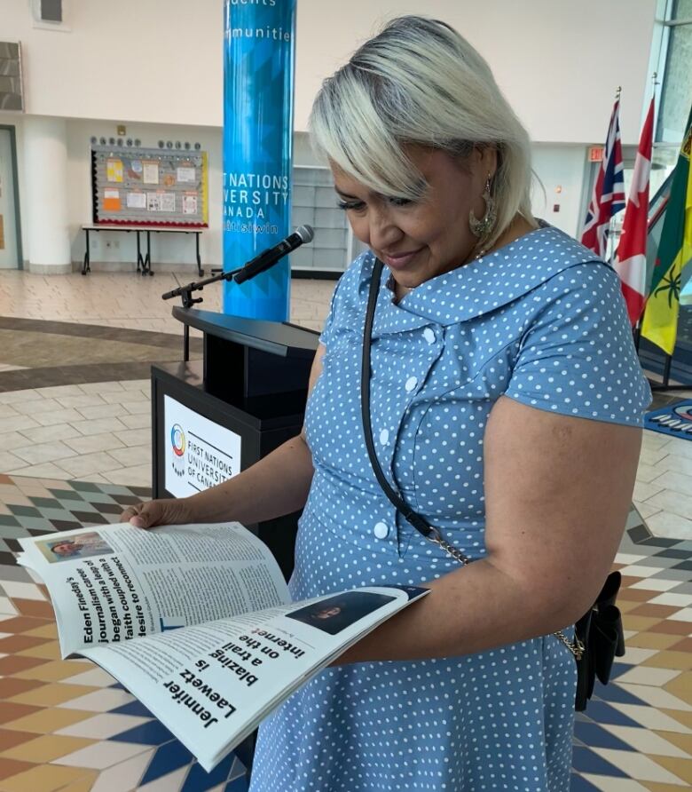 A woman looking down at a magazine. 