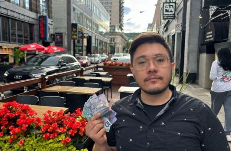 A man holding cash while sitting on a patio