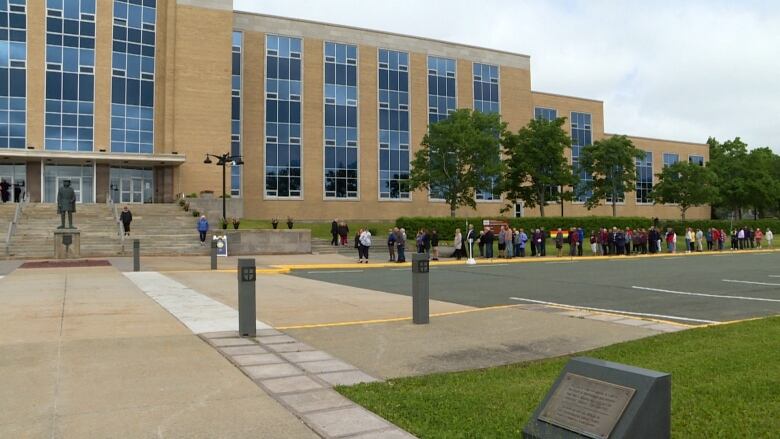 A long line of people stretch down a sidewalk.