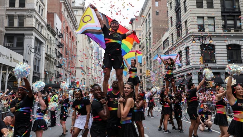 A person holding a flag is held up in the air by others during a parade.