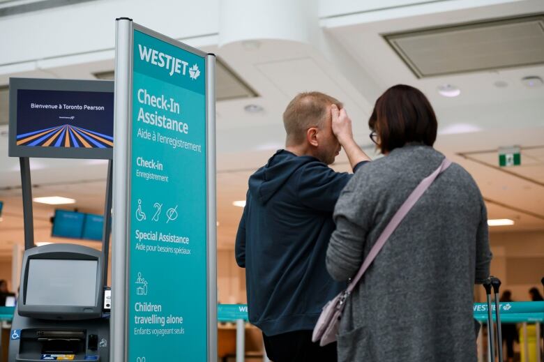 A man holds his head while waiting in an airport.