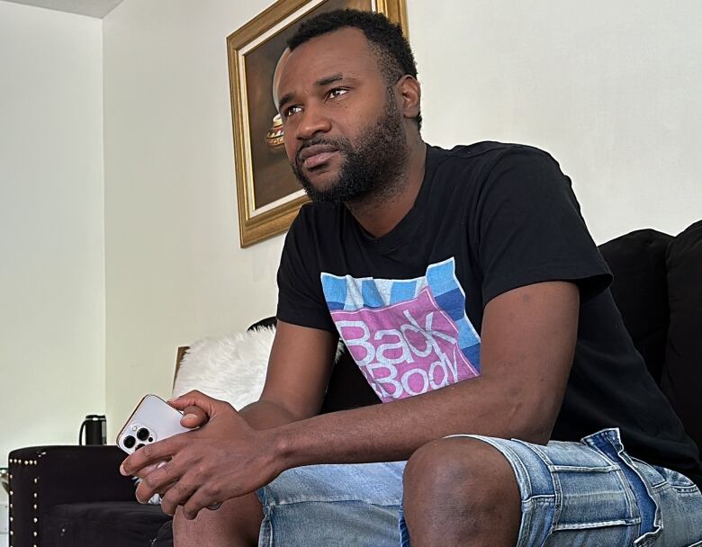 A man sits on a couch in his home.