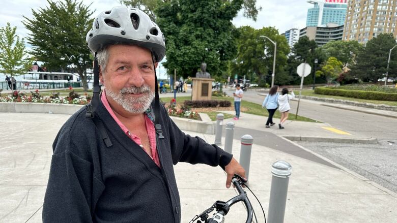 A man in a cycling helmet standing with his bike.