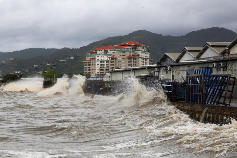 Large waves crash against a sea wall.