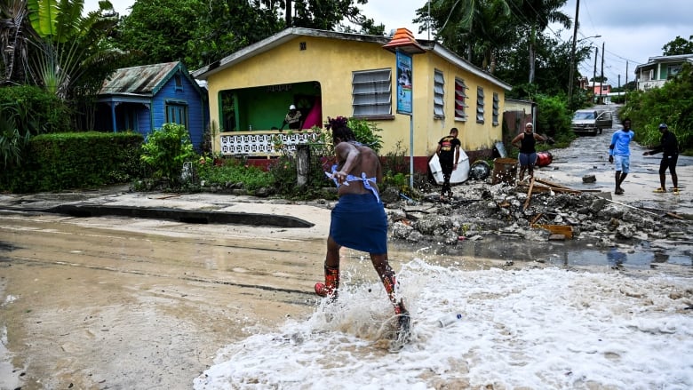 A person runs from flowing water that is flooding a street.