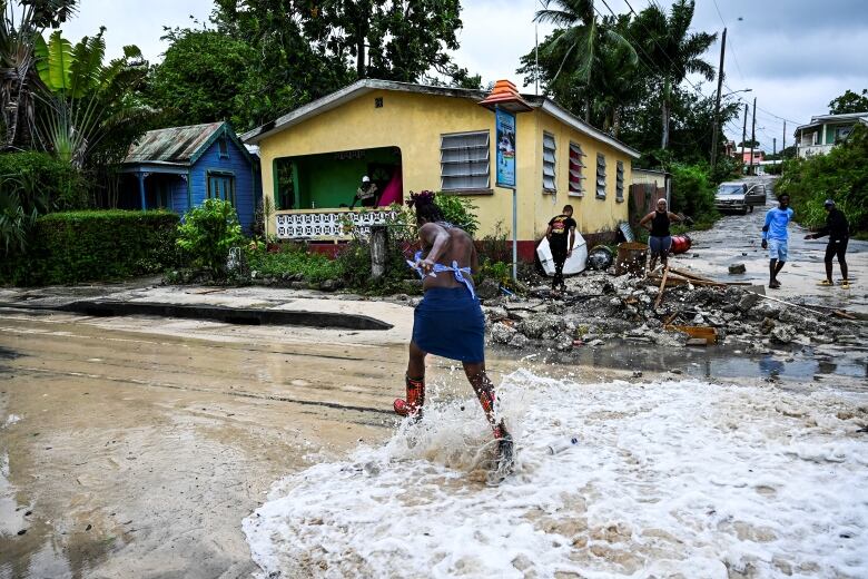 A person runs from flowing water that is flooding a street.