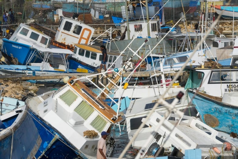 People walk amid damaged fishing vessels.