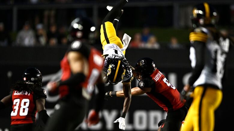 Hamilton Tiger-Cats' Luther Hakunavanhu (81) gets flipped upside down as he is tackled by Ottawa Redblacks' Jovan Santos-Knox (5) Ottawa Redblacks' Jovan Santos-Knox (5) during second half CFL football action in Ottawa on Sunday, June 30, 2024. 