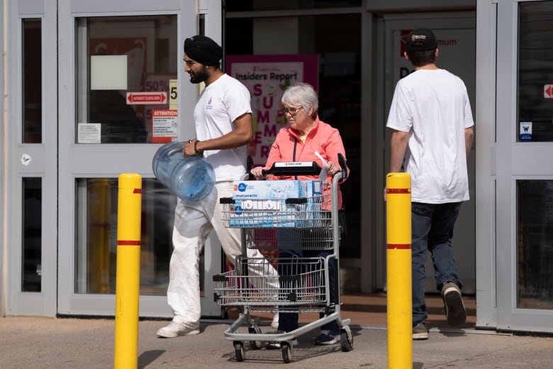 Shoppers exit a grocery store with cans and bottles of water as residents living in the Halifax region are being asked to boil water for one minute before consumption on Tuesday, July 2, 2024.