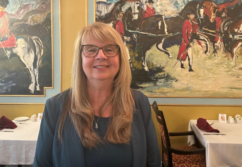 A woman stands in the dining room of a hotel. 