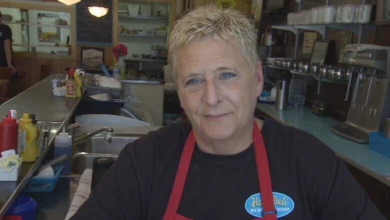 A woman stands near a sink in a restaurant.