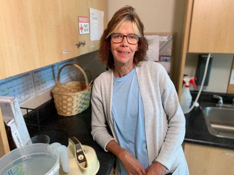 Woman stands in kitchen.