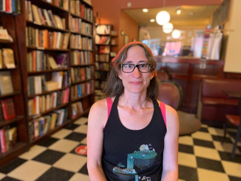 Woman stands near bookshelf.