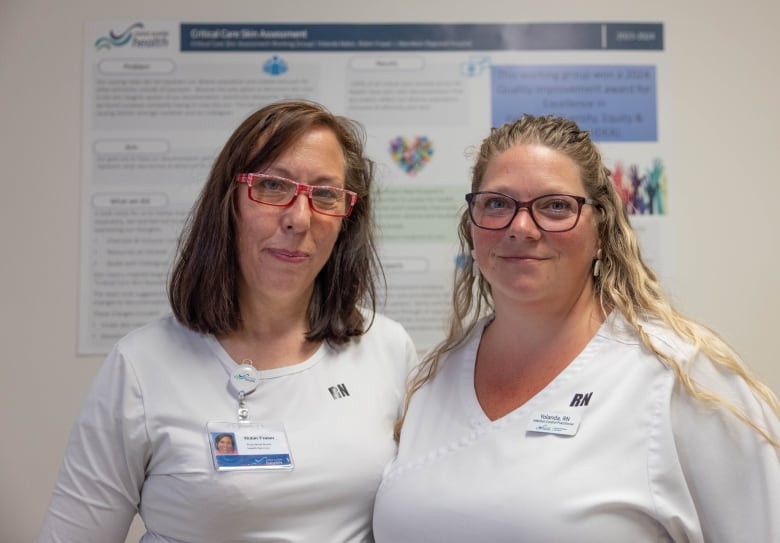 Two women in nurse uniforms pose together.