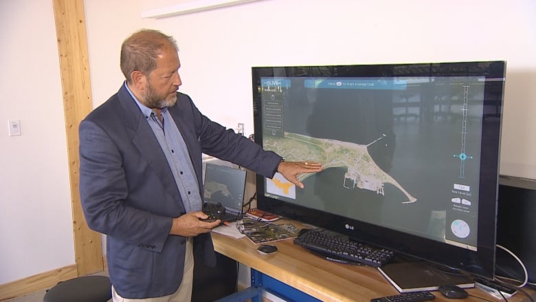 A man points at a map on a TV screen. 