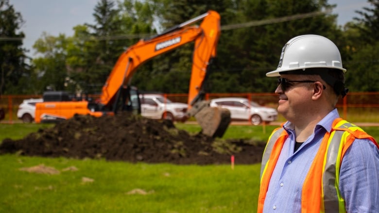 A man in hard hat stands by a construction site.