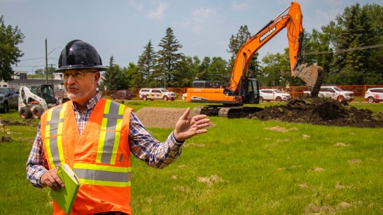 A man in hard hat stands by a construction site.