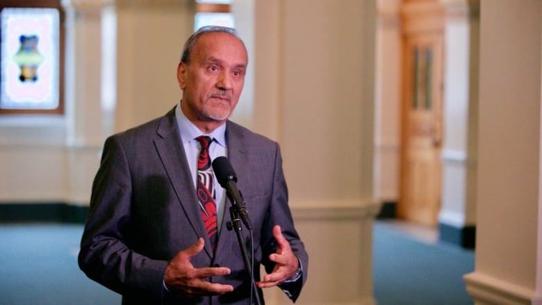 A man in a suit stands at a microphone. 