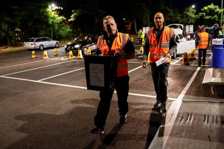 two men carry ballot boxes