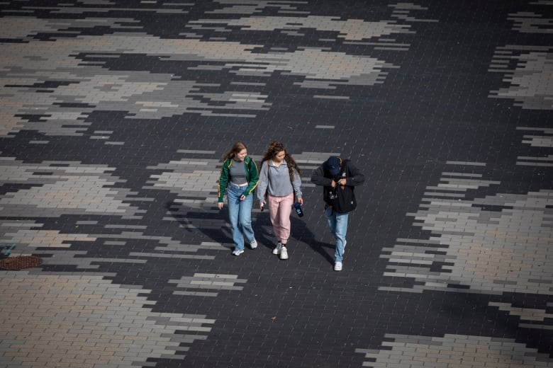 Three students walk across campus.