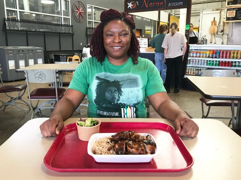 A woman sits at a table with food in front of her.