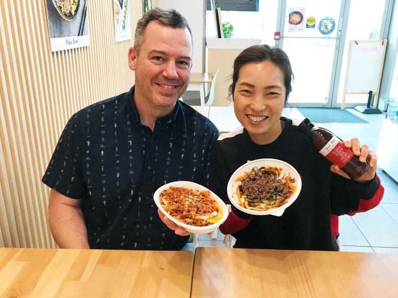 A woman and a man hold a plate of food.