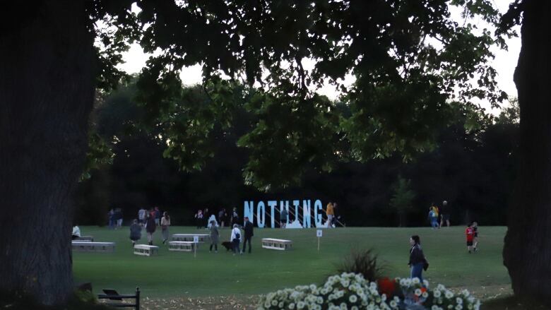 A field with people and a large art installation sign that says 