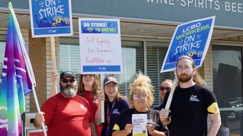 A group of people stand together outside holding picket signs. 