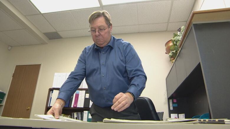 Steve Nixon looks through community papers on his desk in Saskatoon.