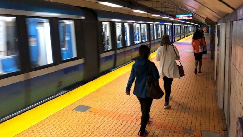 People walk on a subway platform.