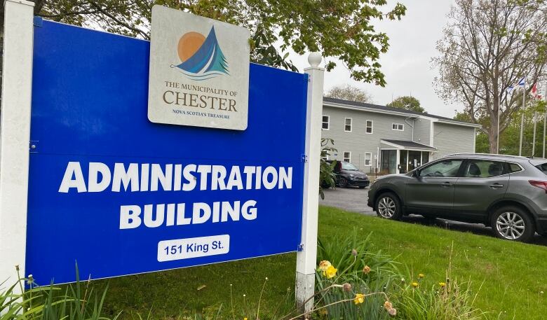 A blue sign says administration building, and features the Chester municipality's white logo. A low-rise grey building can be seen behind the sign across a parking lot