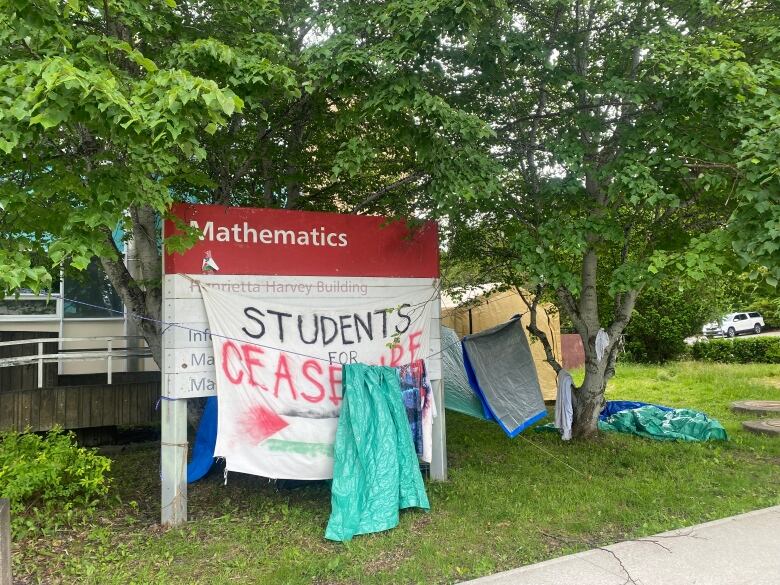 Tents set up behind sign with tarp draped over that states, 