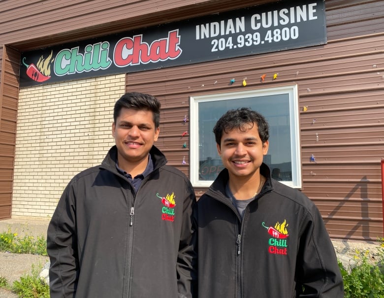 Two brothers stand smiling outside of their parents restaurant Chili Chat. 