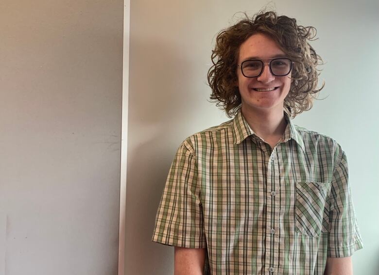 A man stands in front of a blank wall for a photo.