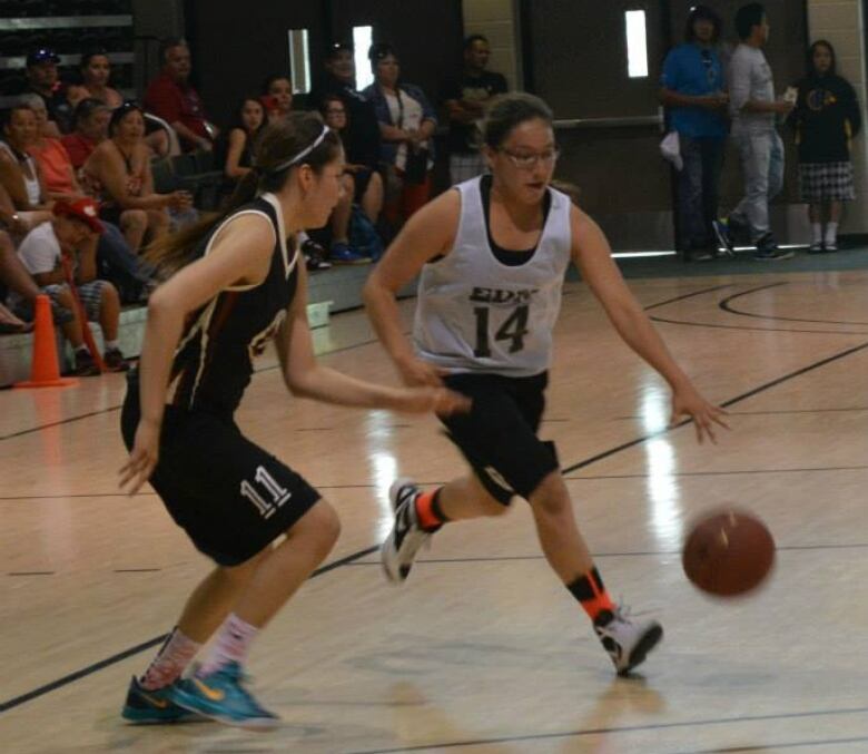 Two girls play basketball.