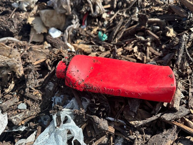 A red old spice bottle in what looks like garbage-y dirt.