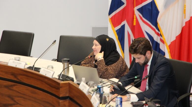 Woman, sitting at council table, speaking into microphone. 