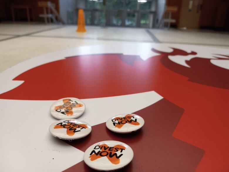 A closeup of a table with a few Divest Now buttons, with a lobby in the background.