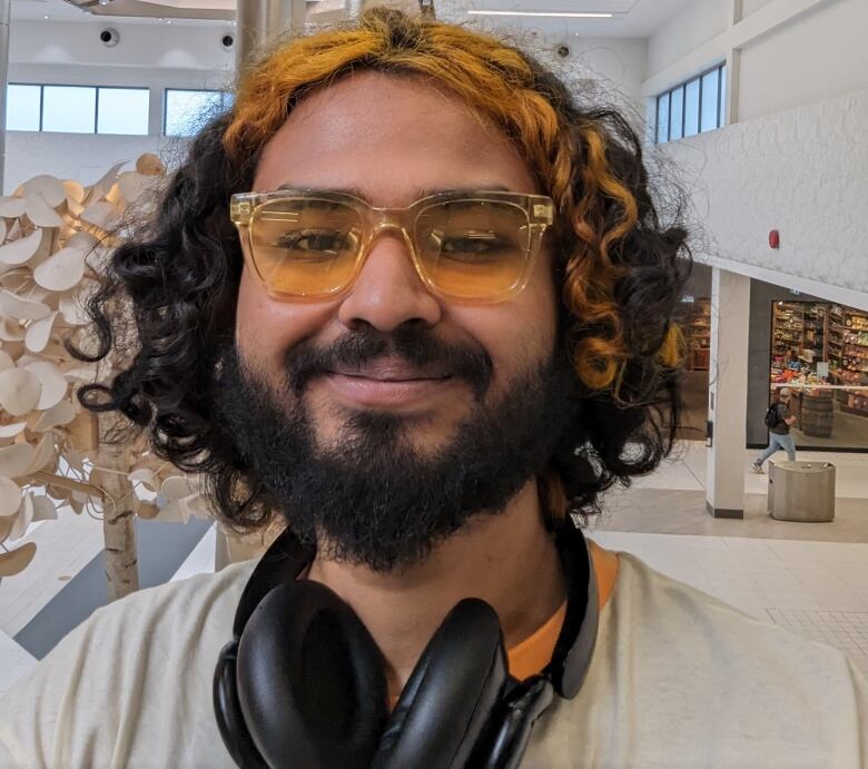 Man with beard, curly hair and yellow glasses.